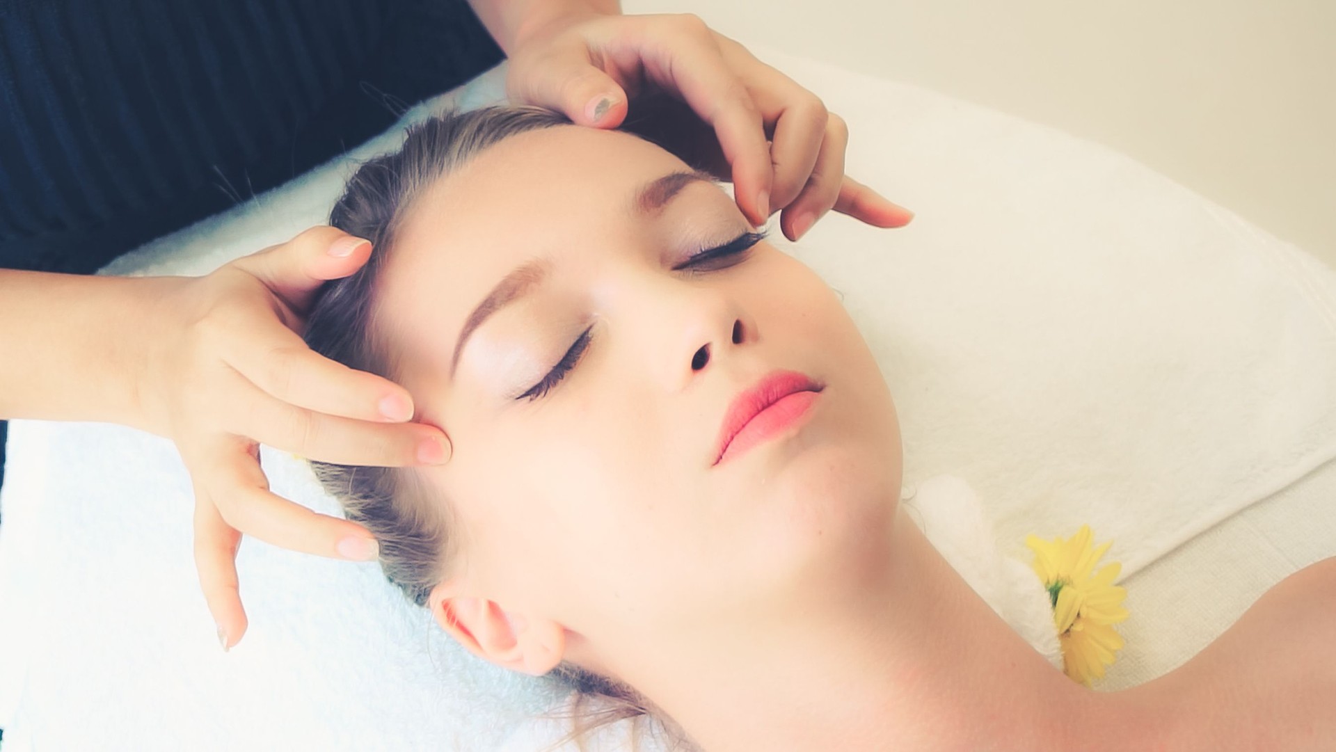 Mulher recebe massagem facial e cabeça em spa de luxo.