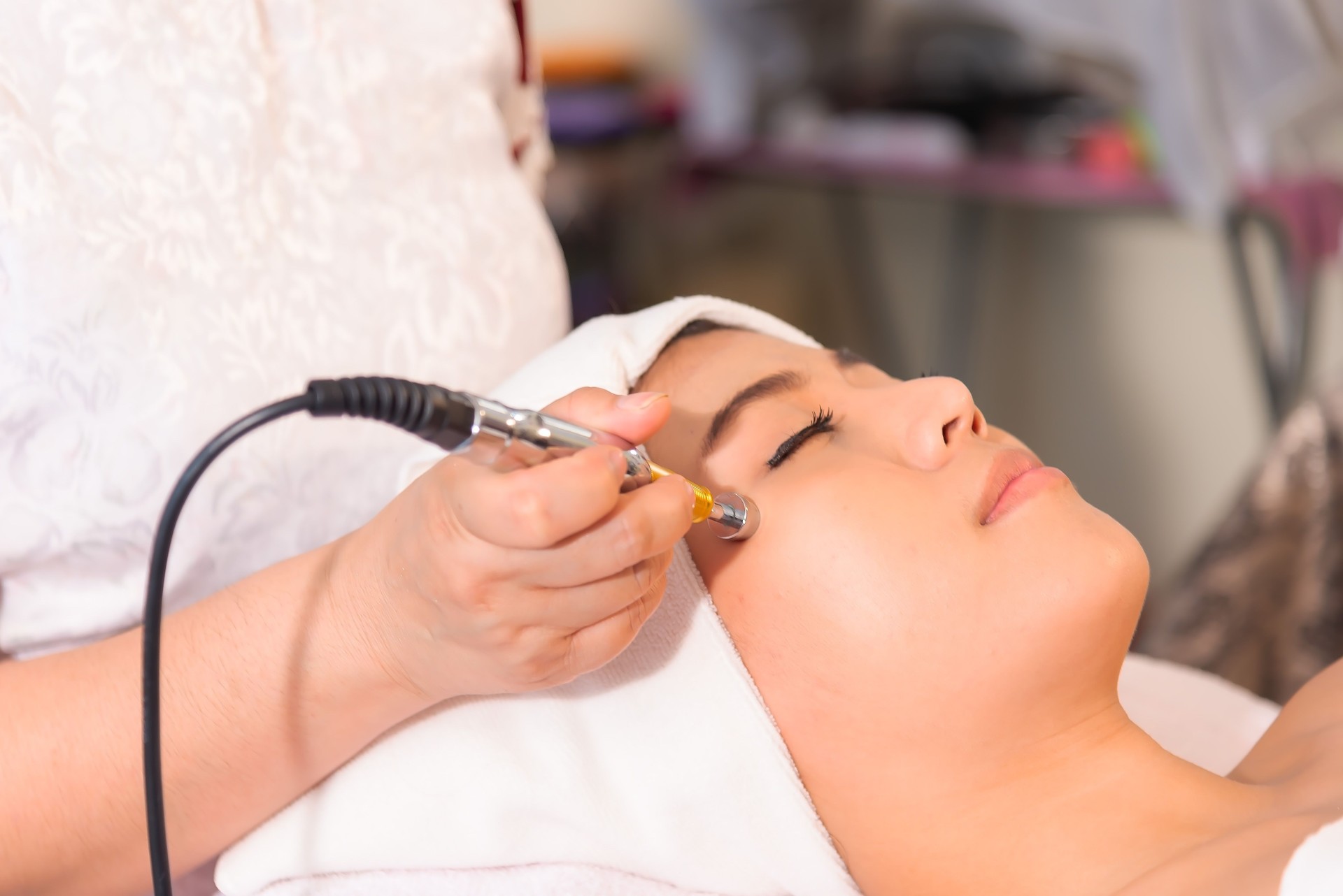 Tratamento rejuvenescedor facial terapia clínica de salão de beleza do spa. Linda jovem mulher asiática ficando elevando antienvelhecimento, massagem de rosto e pele em cosmetologia estética de eletroporação facial terapia. Conceito saudável